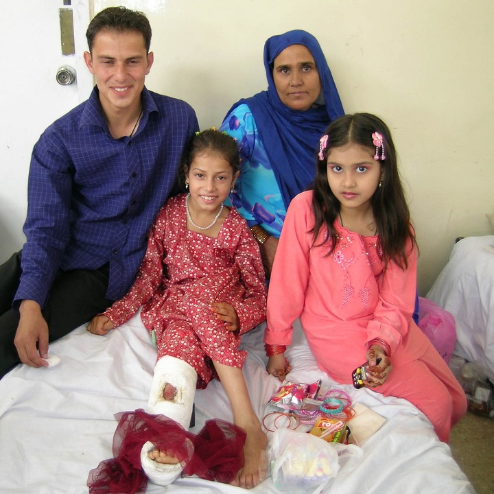 Child with broken leg in plaster sitting on hospital bed with family